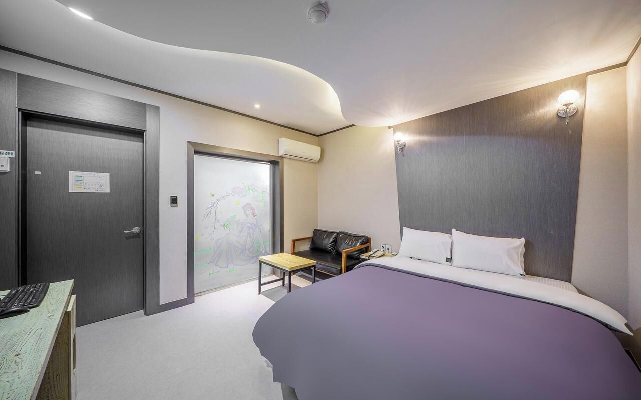 Ein modernes Hotelzimmer mit Bett, Schreibtisch und Sitzecke.