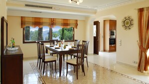 A dining area with a large table, chairs, and a view of the outdoors. - Villa Argyro (Corfu)