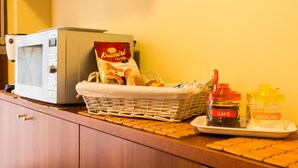 A kitchen counter with a microwave, a basket of bread, and two condiment jars labeled "CAFÉ" and "AZÚCAR".