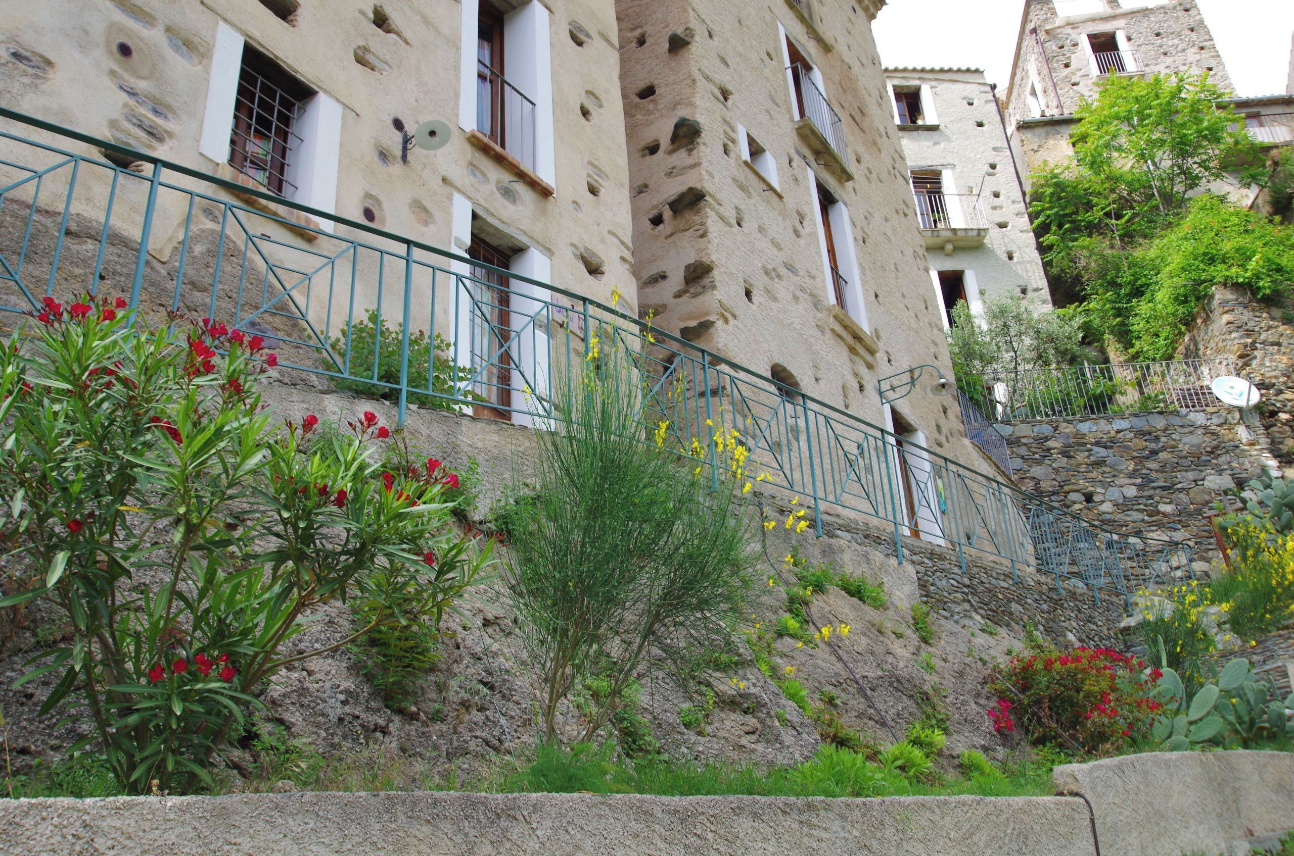 Un bâtiment en pierre doté de balcons et d’un escalier menant à son entrée.