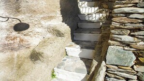 A narrow stone staircase with white steps leading up a stone wall.