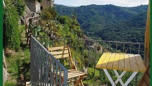 A stone pathway leading to a wooden bench and table set against a mountainous backdrop.