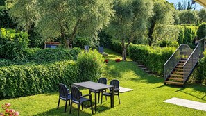 A well-maintained garden with a dining area, a staircase, and a hedge.