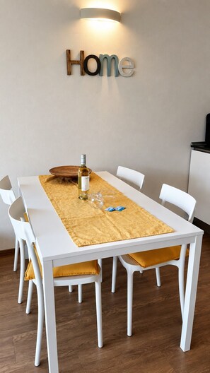 A dining area with a white table, yellow placemat, and a bottle of wine.