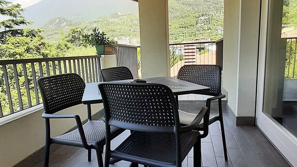 A covered outdoor seating area with a table and chairs, a view of the surrounding landscape, and a wooden ceiling. - Vacation apartment Anna in Casa Pimi under German ital. Management and support (Malcesine)