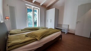 A bedroom with two beds, a window, a radiator, and a wardrobe. - Vacation apartment Anna in Casa Pimi under German ital. Management and support (Malcesine)