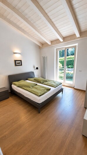 Una camera da letto con un letto grande, un termosifone, un quadro appeso e vista sul verde dalla finestra.