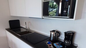 A modern kitchen with white cabinetry, a black countertop, and a built-in microwave. - Vacation apartment Anna in Casa Pimi under German ital. Management and support (Malcesine)