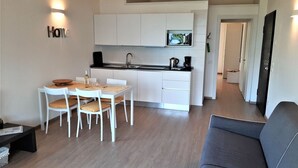 A modern kitchen with white cabinets, a black countertop, and a dining area with a table and chairs. - Vacation apartment Anna in Casa Pimi under German ital. Management and support (Malcesine)
