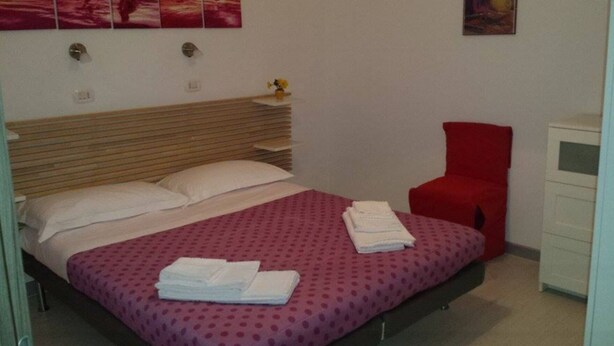 A neatly made bed with a pink polka dot bedspread, white pillows, and folded towels on the side. - La Tavernetta Apartment CIN IT077014C201874001 (MATERA)