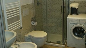 A bathroom with a shower, two toilets, a sink, and a washing machine. - La Tavernetta Apartment CIN IT077014C201874001 (MATERA)