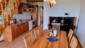 Een houten trap die leidt naar een keuken met een eettafel en stoelen.