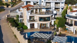 A modern multi-story building with a swimming pool, outdoor seating, and balconies.