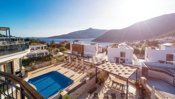 A rooftop pool area with a clear view of the sea and mountains.