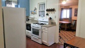 A compact kitchen with a refrigerator, stove, microwave, and a dining area with a table and chairs. - Rustic Cabin (Ruidoso)