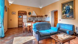 A living room with a blue sofa, a wooden coffee table, and a kitchen area with a microwave and cabinets.