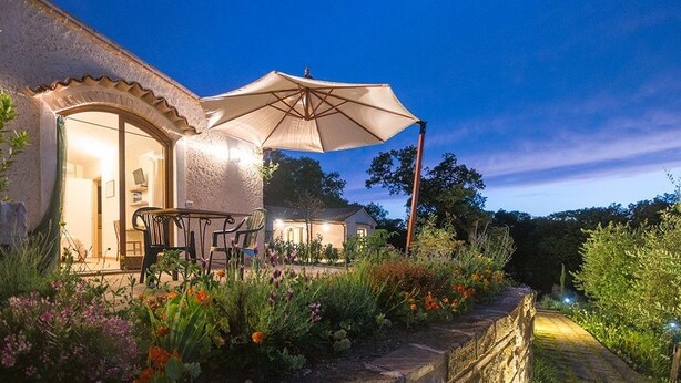 A house with a patio area featuring outdoor furniture and a large umbrella. - IL BORGHETTO Magical property for large groups and families in south Tuscany (saturnia)