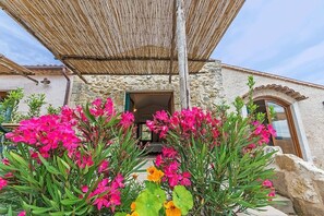 A stone building with a wooden door and a thatched roof structure. - IL BORGHETTO Magical property for large groups and families in south Tuscany (saturnia)