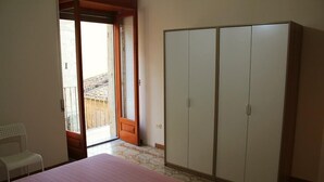 A bedroom with a bed, a wardrobe, and a balcony. - P&G house in historic Sicilian building (Niscemi)