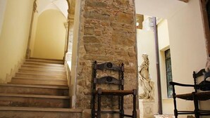 A staircase with stone walls, a wooden chair, and a statue. - P&G house in historic Sicilian building (Niscemi)