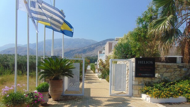 En sti der fører til en hotelindgang med et skilt, der viser "HELIOS Luxury Holiday Residences".