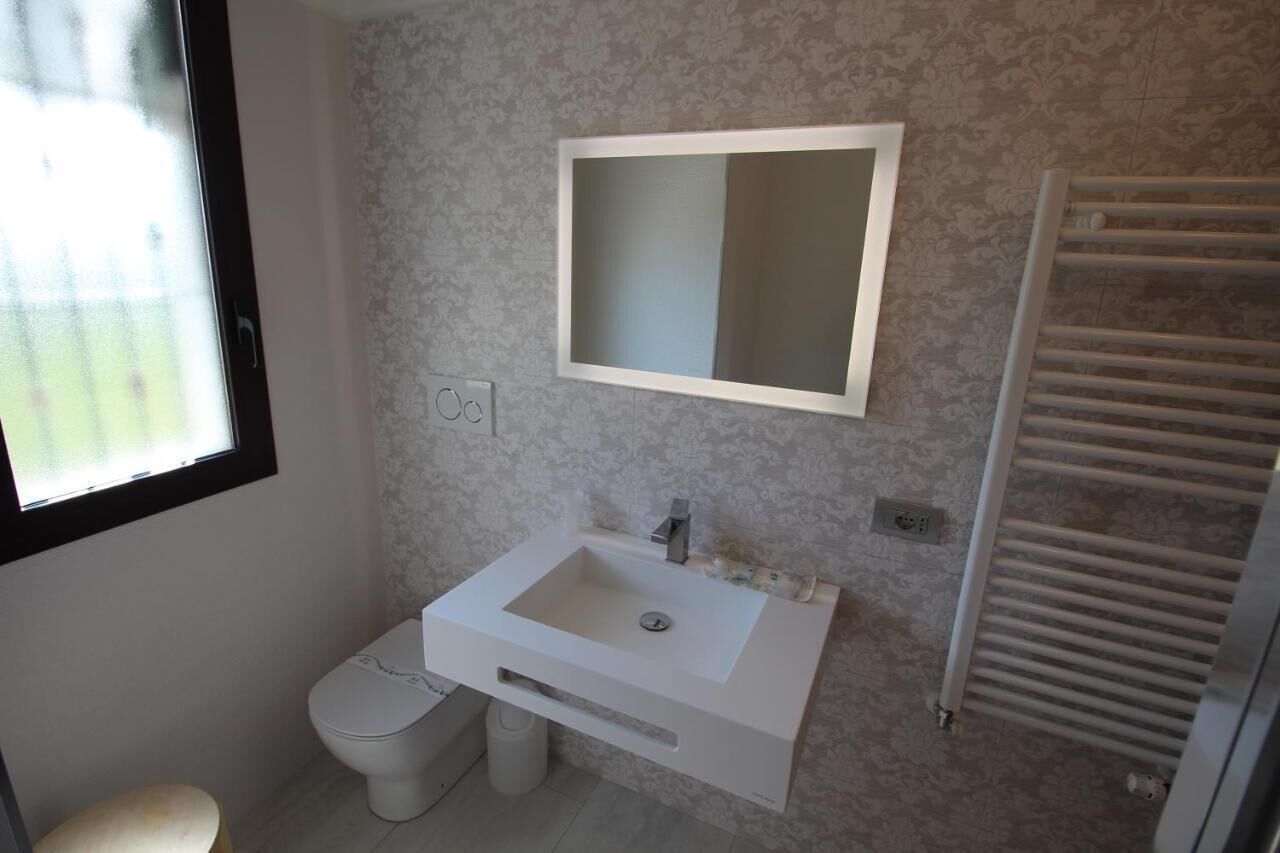 A bathroom with a white sink, a mirror, a toilet, and a towel rack.
