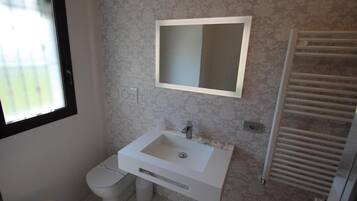 A bathroom with a white sink, a mirror, a toilet, and a towel rack.