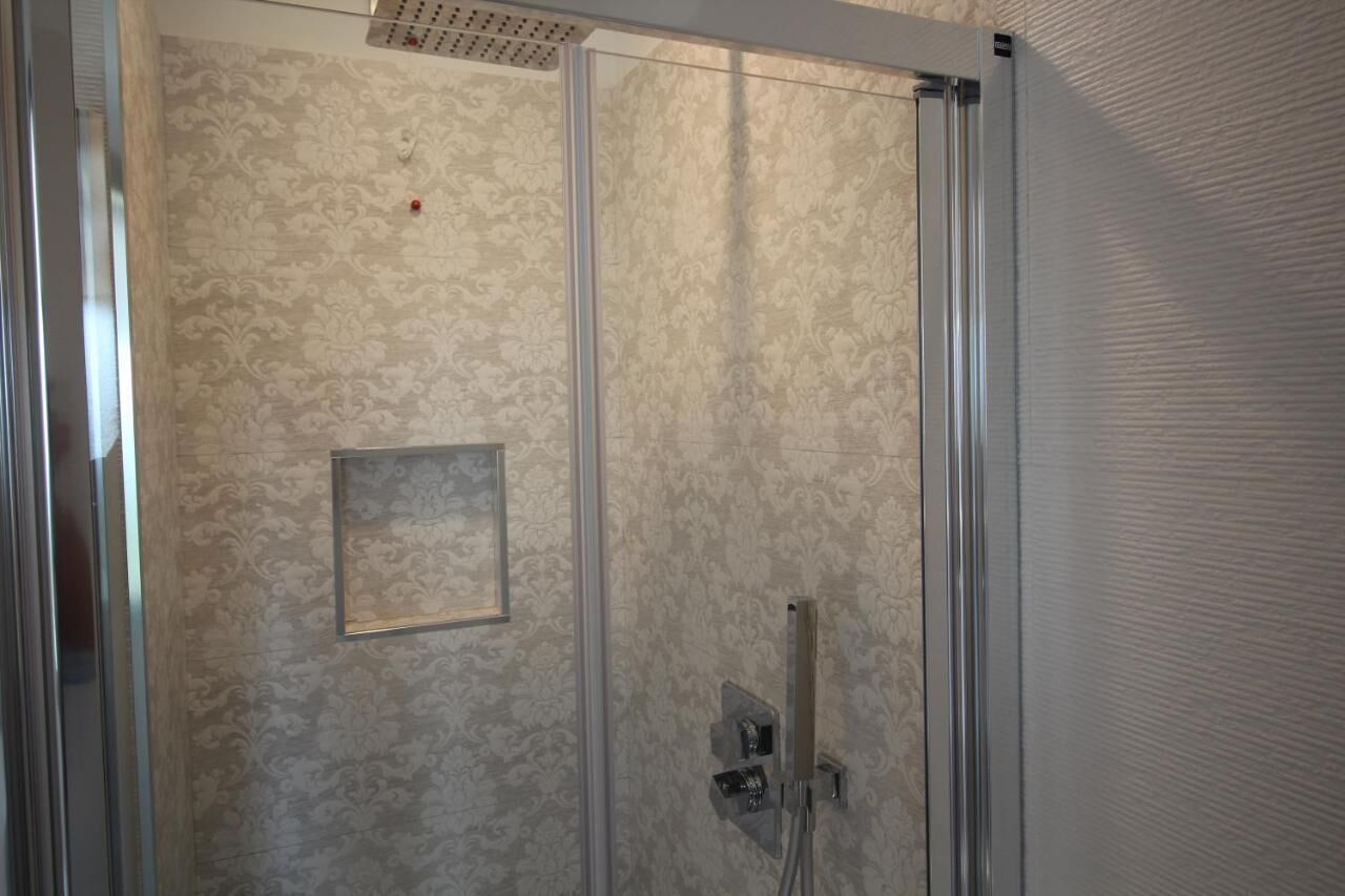 Eine Dusche mit Glastür, Brausekopf und Bedienfeld.