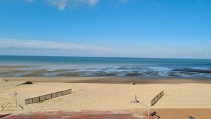 A beach with a clear sky, a sandy shore, and a calm sea.