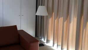 A modern room with a brown sofa, a white wardrobe, and a floor lamp.