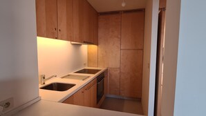A compact kitchen with wooden cabinets, a white countertop, and a built-in oven.