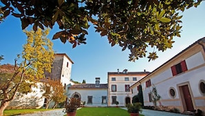 A courtyard with a gravel path, a small lawn, and buildings with red shutters and white walls. - Villa Verecondi Scortecci (Colle Umberto)