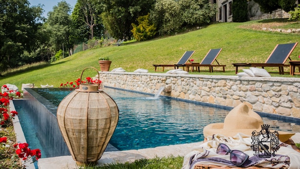 A pool area with lounge chairs, a stone wall, and a large decorative vase. - Villa Verecondi Scortecci (Colle Umberto)