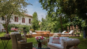 A well-maintained outdoor patio area with wicker furniture, a glass coffee table, and a red patterned rug. - Villa Verecondi Scortecci (Colle Umberto)
