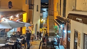 Eine enge Straße mit Außenplätzen und Blick auf einen Hügel in der Ferne.