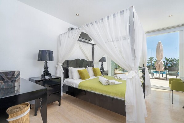 A modern bedroom with a canopy bed, a desk, and a view of the outdoors.