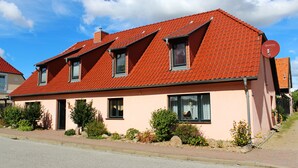 A two-story house with a red-tiled roof, multiple windows, and a satellite dish.