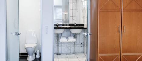 A modern bathroom with a toilet, a glass-enclosed shower, and a vanity with two sinks.