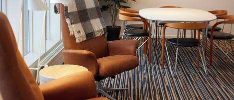 A modern room with a brown leather sofa, a round table, and a striped carpet.