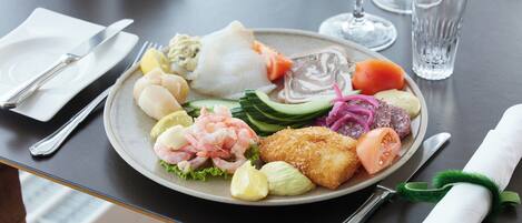 A plate of assorted seafood and vegetables on a table with cutlery and glasses.