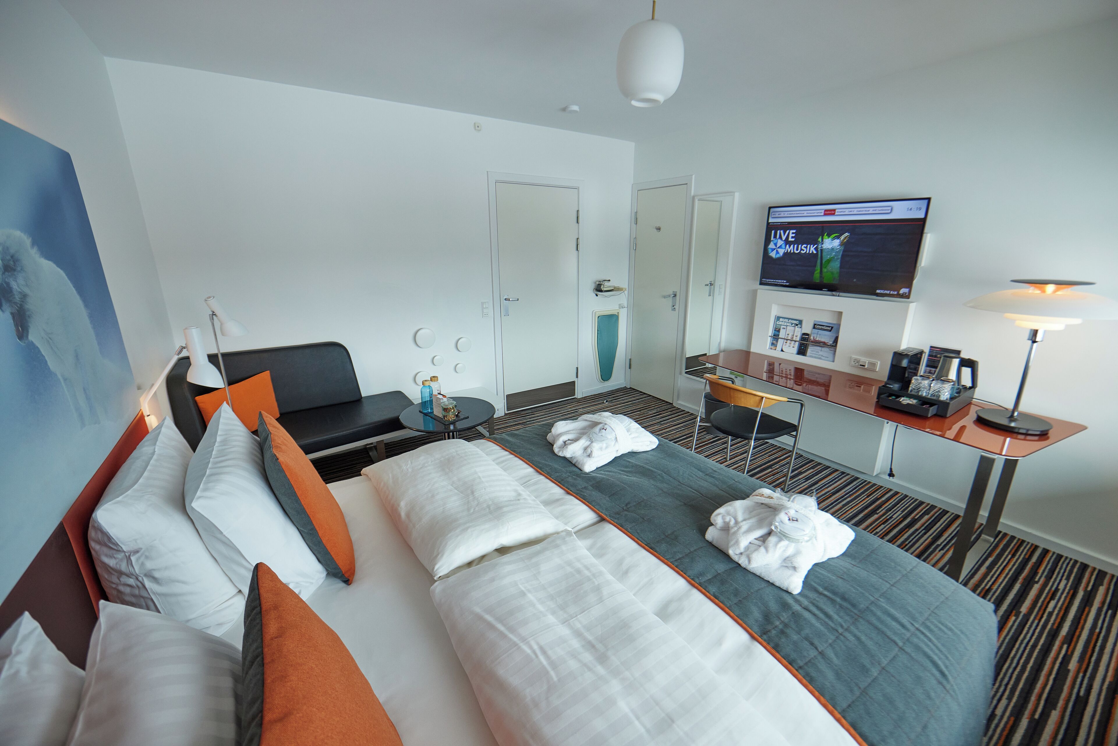 Una habitación de hotel con cama, escritorio, televisor y zona de estar.
