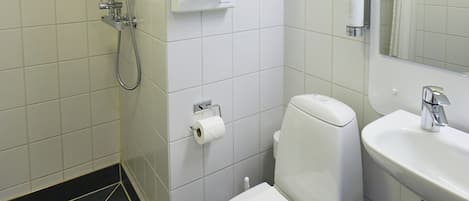 Un baño moderno con inodoro, lavabo, espejo, ducha y dispensador de papel higiénico.