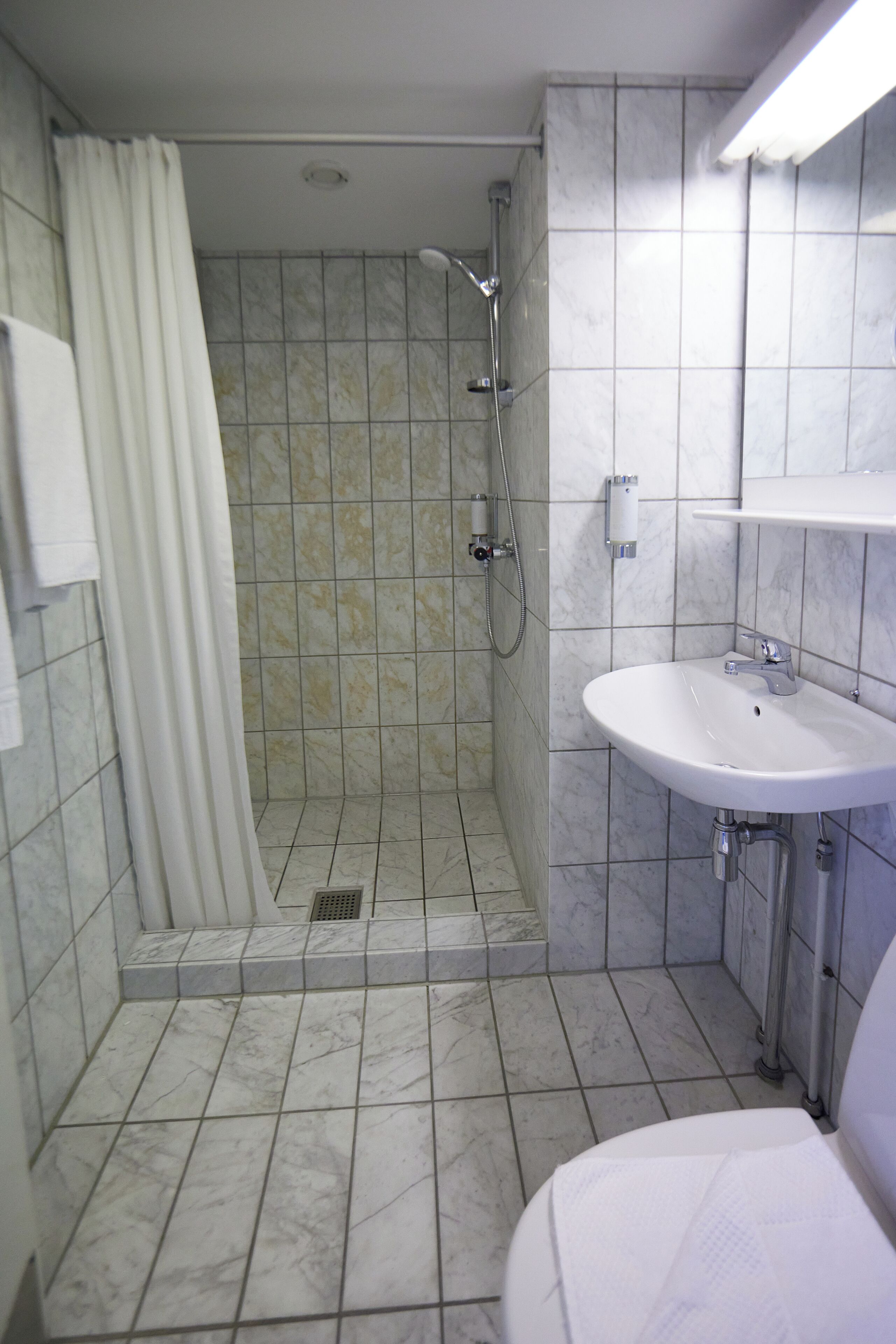 Un baño con ducha, lavamanos e inodoro.