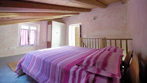 A bedroom with a bed, wooden headboard, and a window with curtains. - Calabria, Medieval Village, Ecotourism, tradition and culture, sea and nature. (Belmonte Calabro)