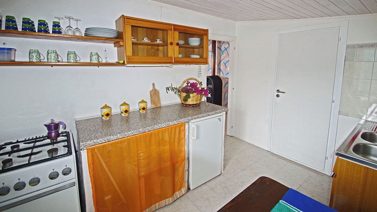 Une cuisine avec des meubles de rangement en bois, un réfrigérateur blanc, une cuisinière à gaz et un évier.