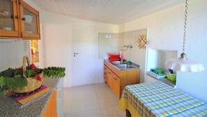 A compact kitchen with a sink, wooden cabinets, and a dining area with a table. - Calabria, Medieval Village, Ecotourism, tradition and culture, sea and nature. (Belmonte Calabro)