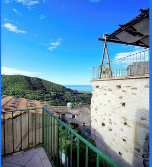Un balcon donnant sur un village côtier et sur des collines.