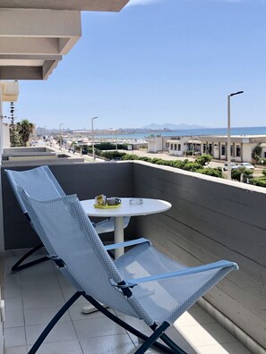 A balcony with a blue mesh chair and a small round table.