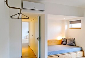 A compact room with a bed, bedside table, and a window.