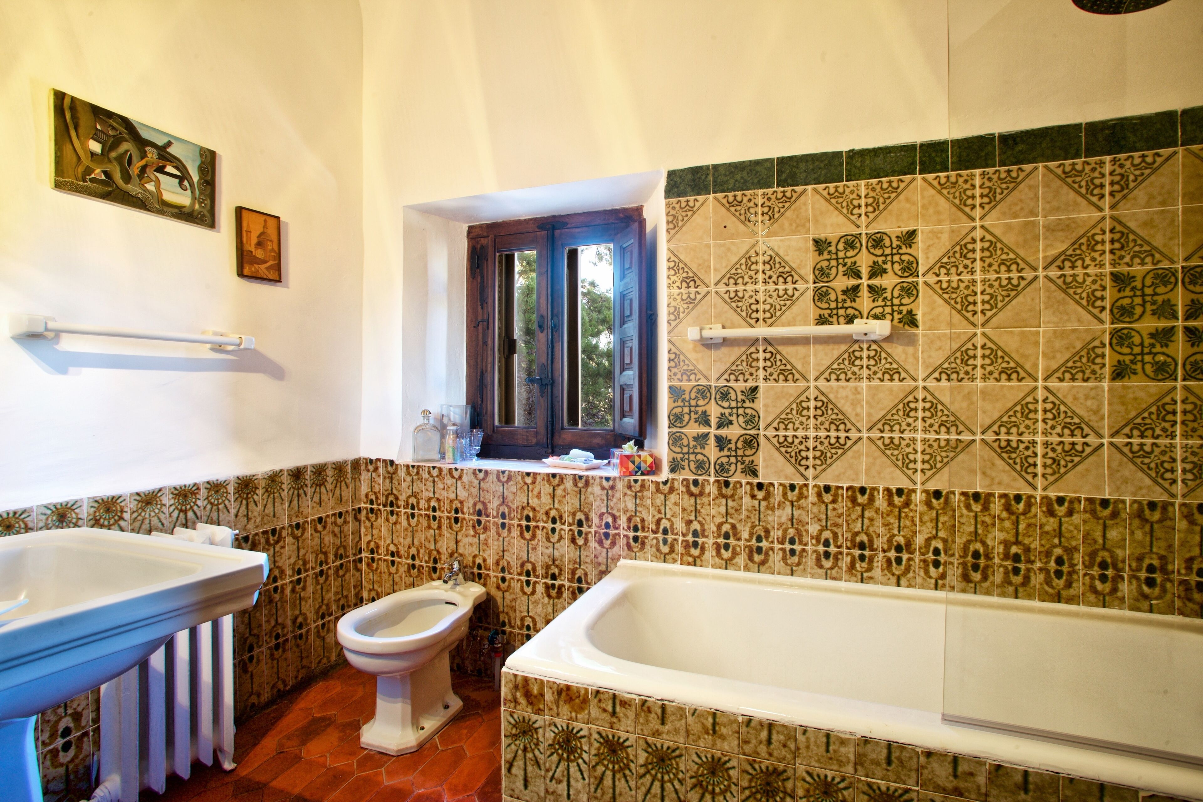 Un bagno con una vasca, un water e un lavandino. Si vede una finestra con vista sull'esterno.